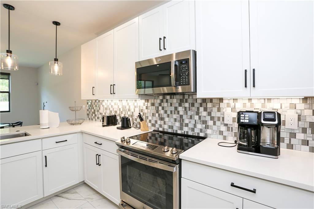 7654 Rockefeller Drive Naples, FL 34119 - Photo 17 of 35 a kitchen with a stove and a microwave