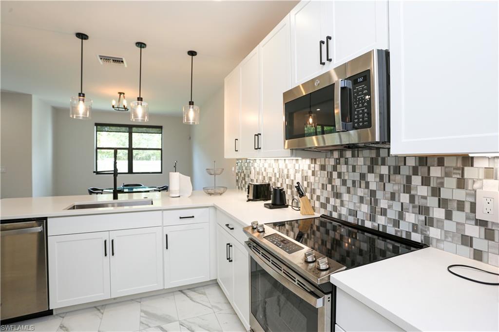 7654 Rockefeller Drive Naples, FL 34119 - Photo 18 of 35 a kitchen that has a sink a stove and microwave