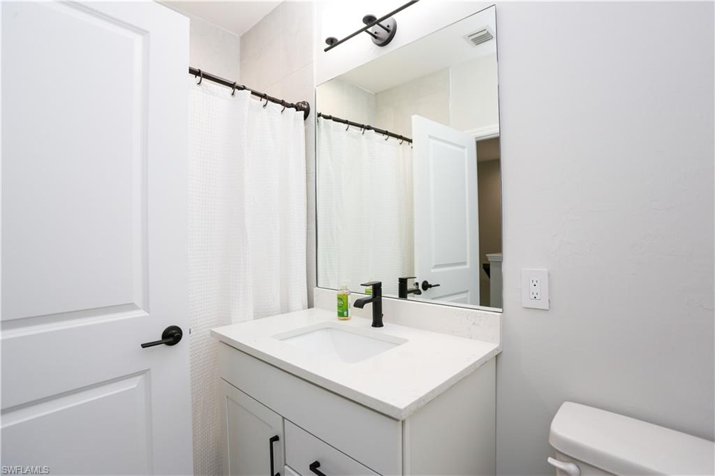 7654 Rockefeller Drive Naples, FL 34119 - Photo 23 of 35 a bathroom with a sink vanity and a mirror