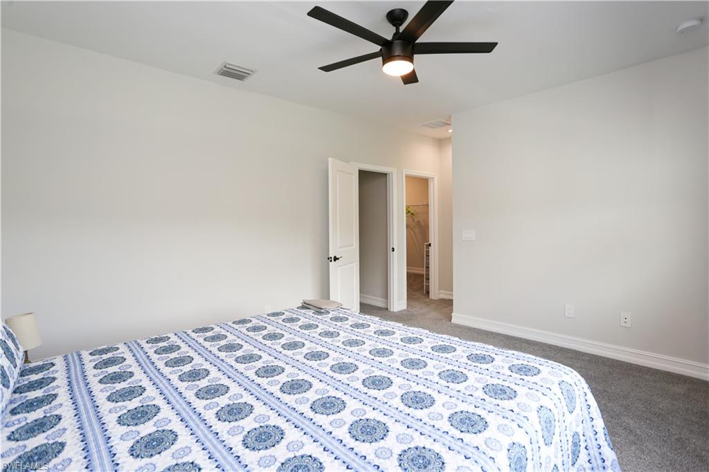 7654 Rockefeller Drive Naples, FL 34119 - Photo 31 of 35 a bedroom with a large bed and a chandelier