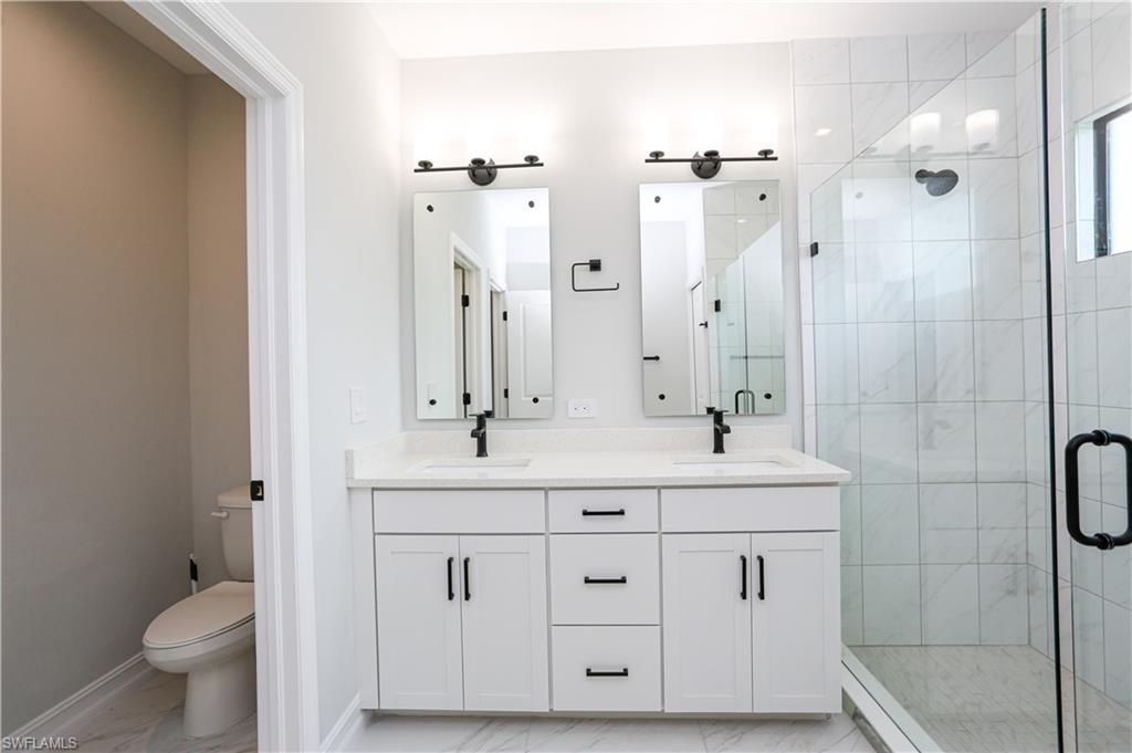 7654 Rockefeller Drive Naples, FL 34119 - Photo 35 of 35 a bathroom with a double vanity sink a toilet a mirror and shower