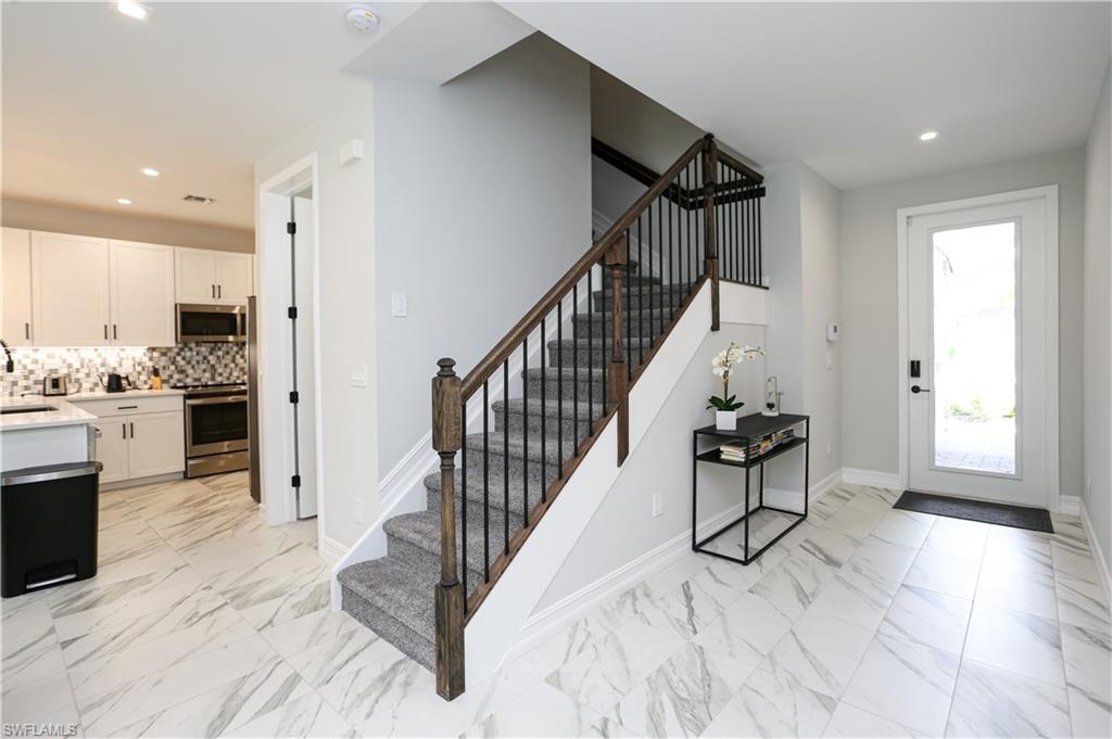 7654 Rockefeller Drive Naples, FL 34119 - Photo 5 of 35 a view of a hallway with wooden floor and staircase