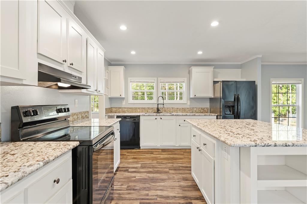 89 Ridge Road Seale, AL 36875 - Photo 11 of 46 Kitchen featuring white cabinetry, light-toned countertops, wood-finish flooring, and a central island with integrated shelving