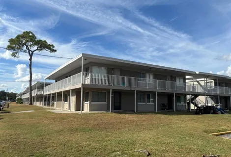 a front view of a building with a garden and trees