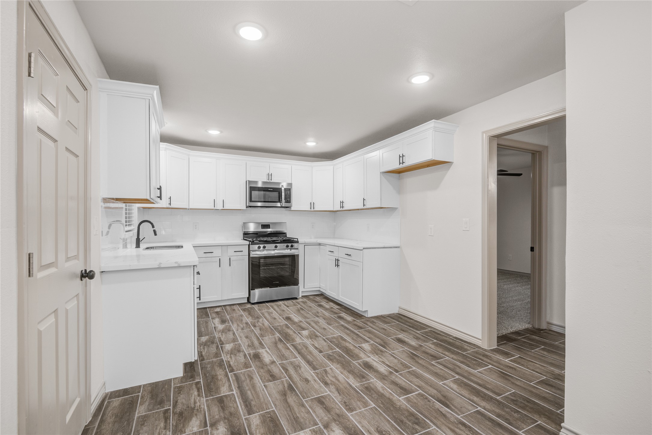 1530 West 10th Street Freeport, TX 77541 - Photo 9 of 32 a kitchen with white cabinets and stainless steel appliances