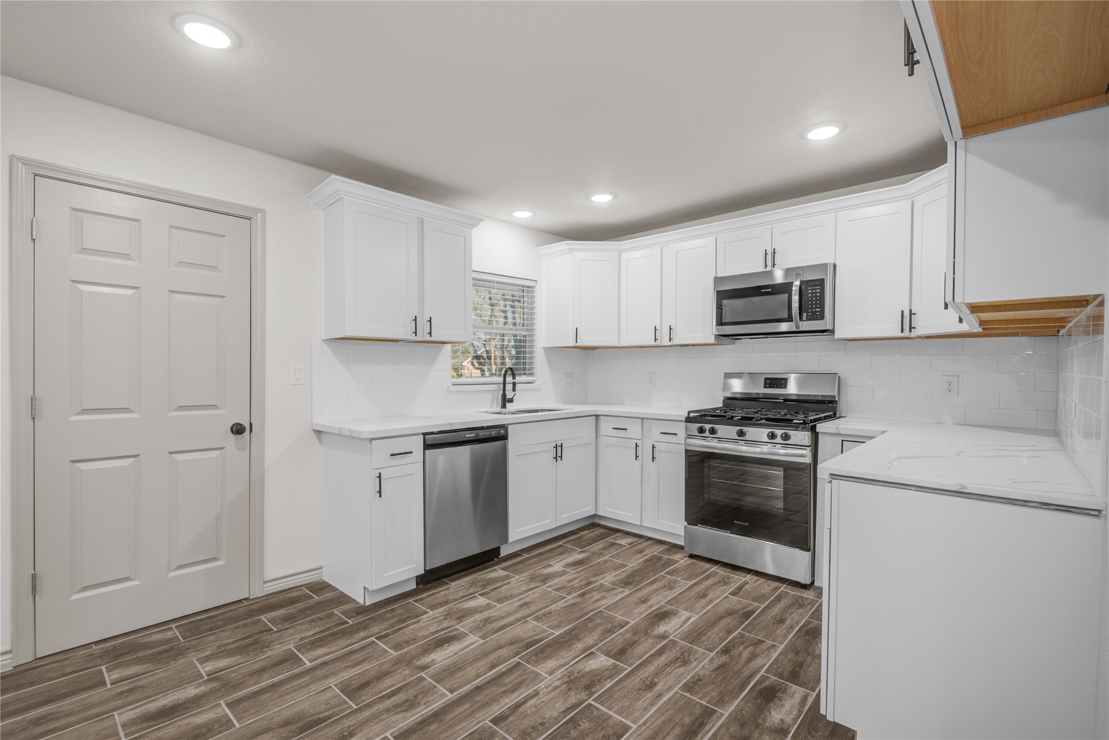 1530 West 10th Street Freeport, TX 77541 - Photo 10 of 32 a kitchen with kitchen island granite countertop a stove top oven a sink dishwasher and a refrigerator with wooden floor