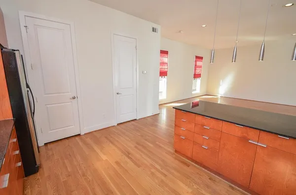 a view of an empty room with wooden floor and a sink