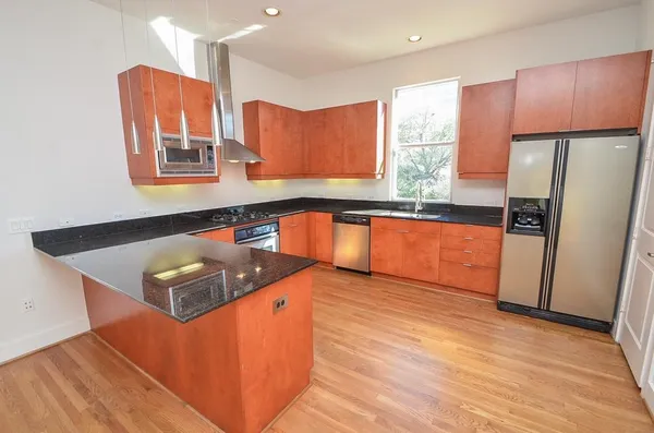 a kitchen with stainless steel appliances granite countertop a sink dishwasher stove and refrigerator with wooden floor