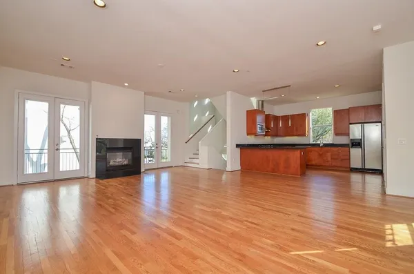 a view of a big room with wooden floor and a kitchen