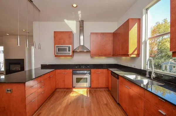 a kitchen with stainless steel appliances granite countertop wooden cabinets a stove a sink and a large window