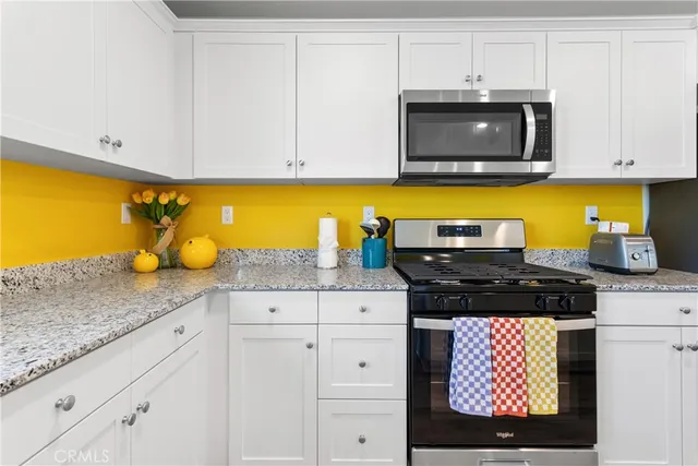 a kitchen with granite countertop white cabinets and stainless steel appliances