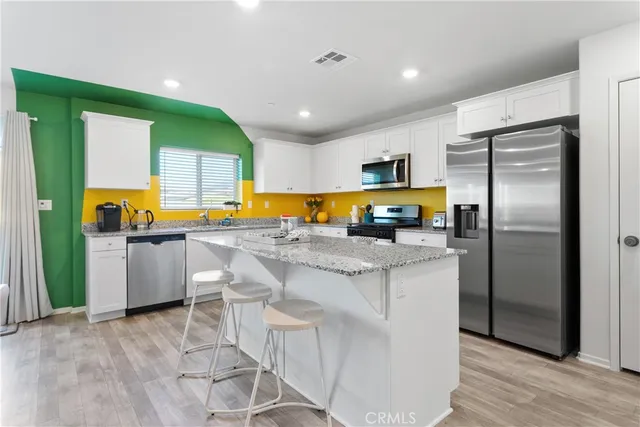 a kitchen with stainless steel appliances granite countertop a refrigerator a stove and a sink