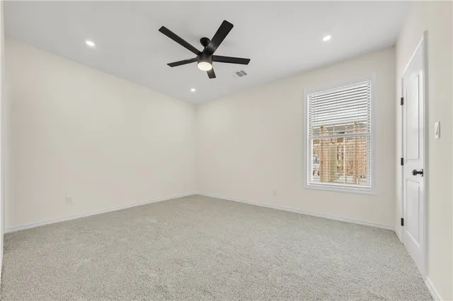 an empty room with windows and ceiling fan
