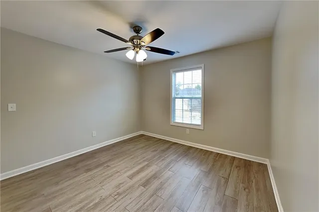 an empty room with wooden floor fan and windows