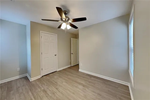 an empty room with wooden floor closet and fan
