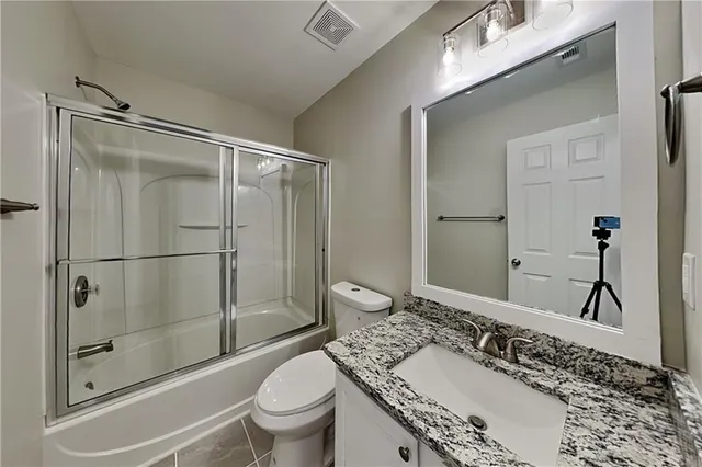 a bathroom with a granite countertop sink toilet and shower