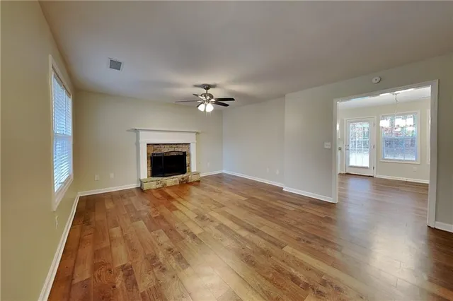 a view of an empty room with wooden floor and fireplace