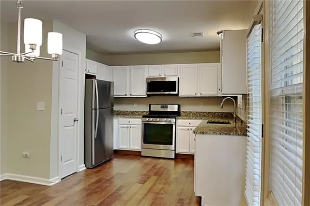 a kitchen with stainless steel appliances granite countertop a refrigerator stove and sink