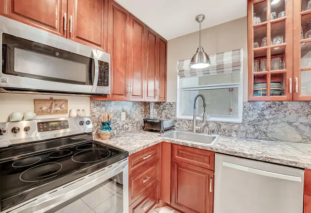 a kitchen with stainless steel appliances granite countertop a refrigerator stove a sink and dishwasher with wooden floor