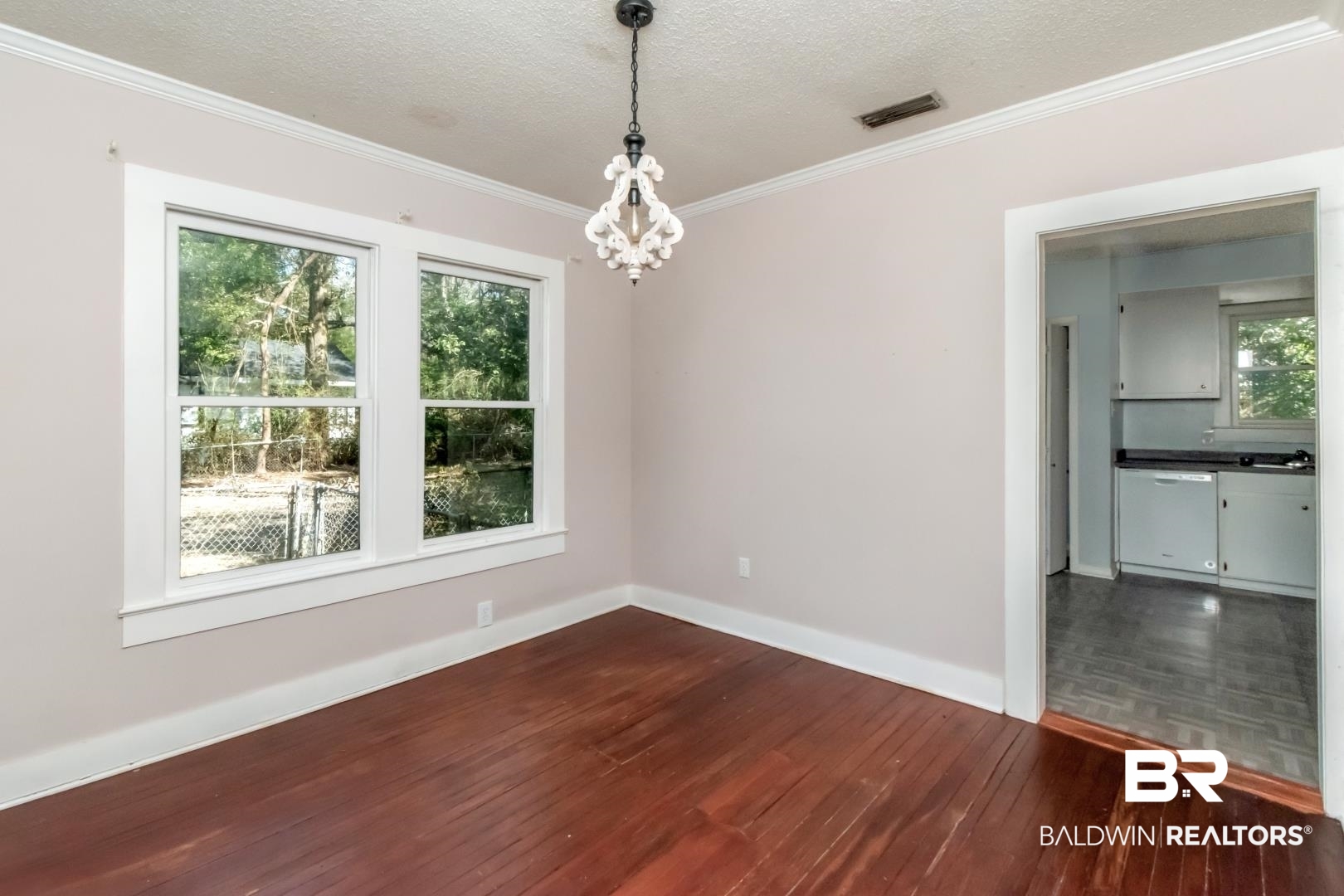 731 Jemison Street Mobile, AL 36606 - Photo 14 of 27 Empty room featuring dark wood-style flooring, a textured ceiling, hanging lights, and ornamental molding