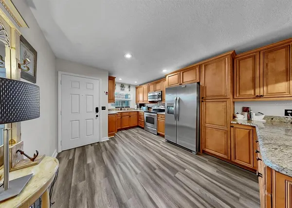 a kitchen with stainless steel appliances granite countertop a stove a sink dishwasher a refrigerator and a granite counter tops with wooden cabinets