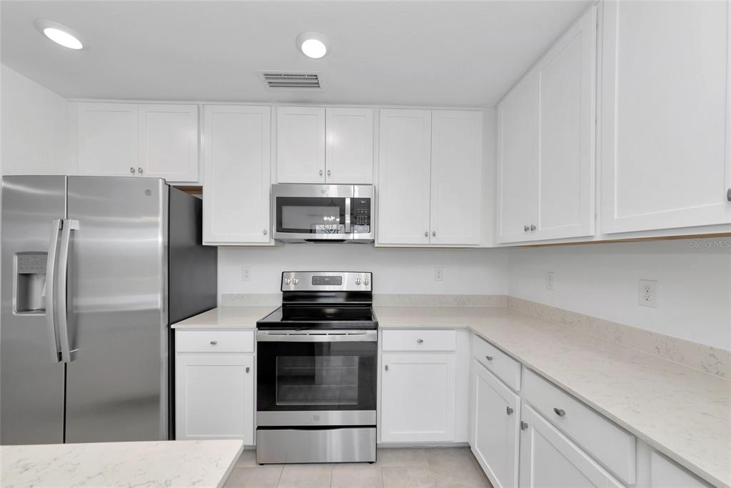 18008 Gawthrop Drive, Unit 101 Lakewood Ranch, FL 34211 - Photo 11 of 56 a kitchen with white cabinets and stainless steel appliances