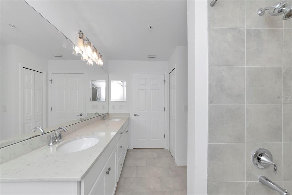 18008 Gawthrop Drive, Unit 101 Lakewood Ranch, FL 34211 - Photo 26 of 56 a bathroom with a double vanity sink and mirror with shower