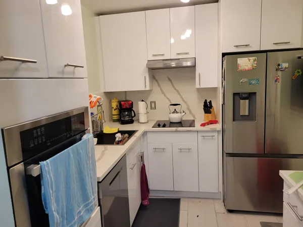 a kitchen with white cabinets and refrigerator