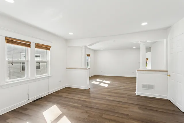 a view of empty room with wooden floor and fan