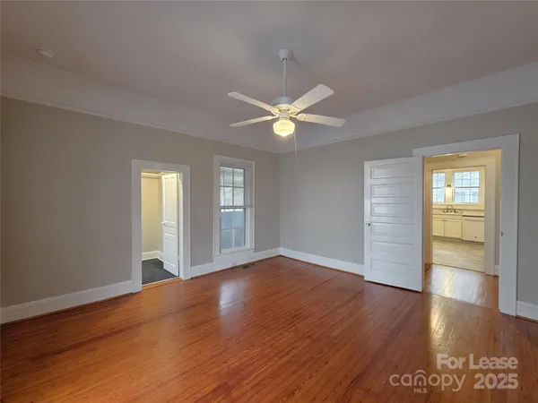 a view of an empty room with window and wooden floor