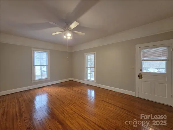 a view of an empty room with wooden floor and window
