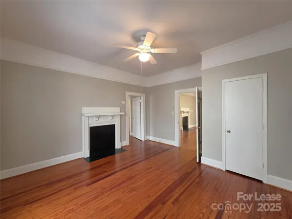 a view of an empty room with wooden floor fireplace and a window
