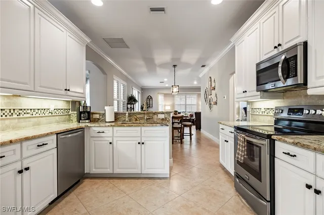 a kitchen with stainless steel appliances granite countertop a stove top oven a sink dishwasher and white cabinets