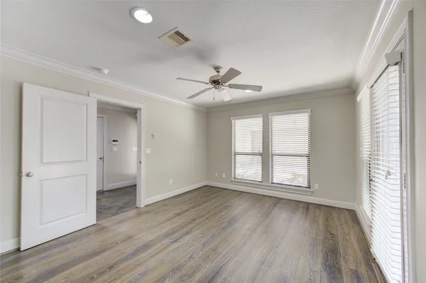 an empty room with wooden floor and windows with curtains