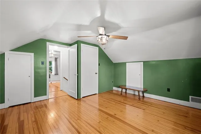 a view of a room with wooden floor ceiling fan and windows
