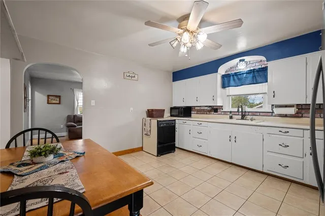 a kitchen with a stove a sink dishwasher a dining table and chairs with wooden floor