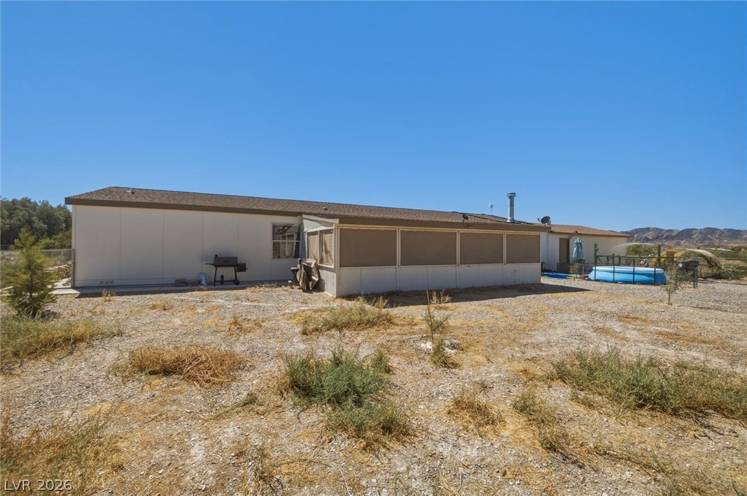 2380 West Simkins Road Pahrump, NV 89060 - Photo 30 of 38 A spacious desert lot surrounds this single-level home with an enclosed rear porch under clear skies.