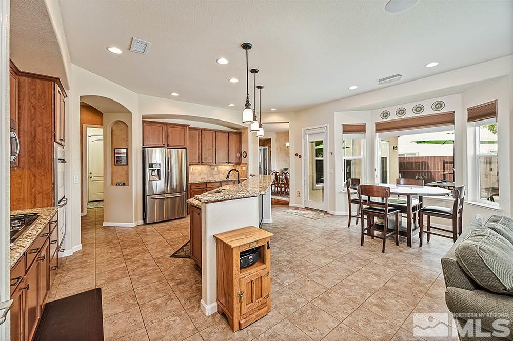 2905 Bull Rider Drive Reno, NV 89521 - Photo 17 of 33 a kitchen with stainless steel appliances kitchen island granite countertop dining table chairs and a living room view