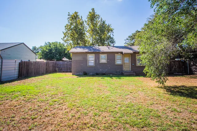 a view of a house with a yard and a large tree