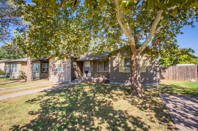 a front view of a house with a tree yard and outdoor seating