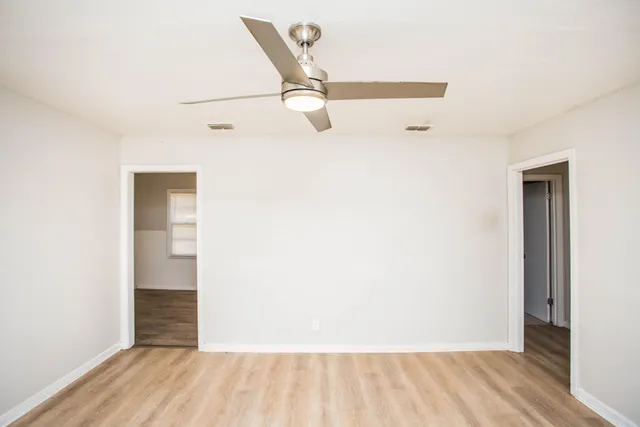 an empty room with wooden floor and windows
