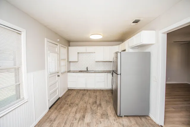 a large white kitchen with a refrigerator a sink and white cabinets