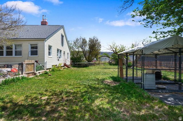 137 West 200 S Street Fairview, UT 84629 - Photo 22 of 34 Spacious grassy yard featuring a chain-link fence, established trees, and a covered outdoor enclosure