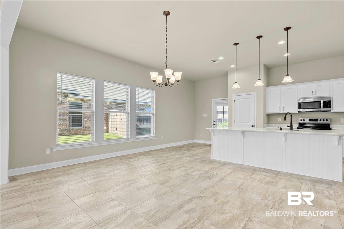 1112 Stella Road Foley, AL 36535 - Photo 8 of 33 Kitchen with white cabinetry, hanging lights, stainless steel appliances, a kitchen bar, and an island with sink