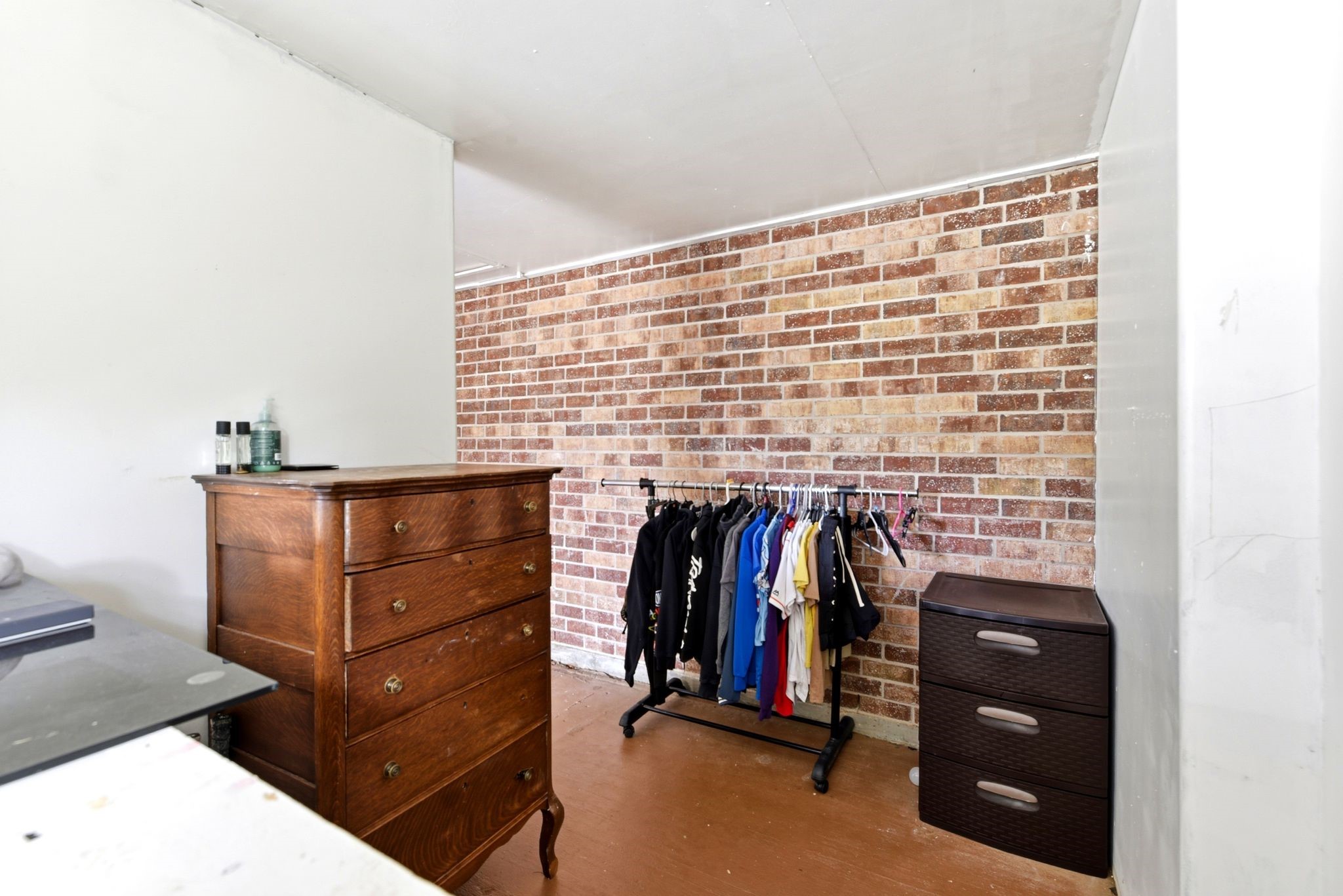 151 Parker Road New Waverly, TX 77358 - Photo 26 of 36 Cozy room featuring a charming brick accent wall, ample storage with a wooden dresser and modern drawer unit, and a convenient clothes rack.
