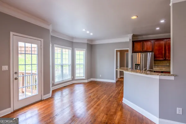 a view of empty room with wooden floor and fan
