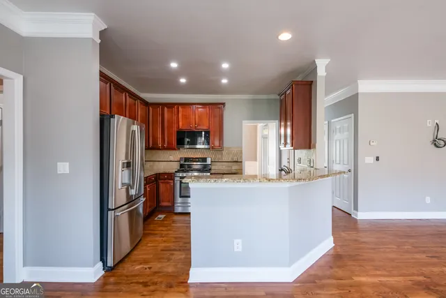 a view of a kitchen with kitchen island a island wooden floor stainless steel appliances and cabinets
