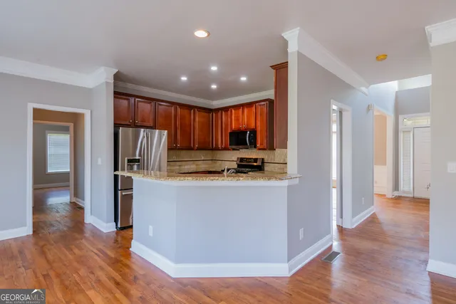 a view of kitchen with stainless steel appliances granite countertop a refrigerator a sink dishwasher and a oven with wooden floor