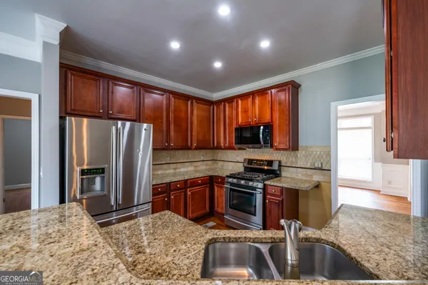 a kitchen with stainless steel appliances granite countertop a stove refrigerator sink and cabinets