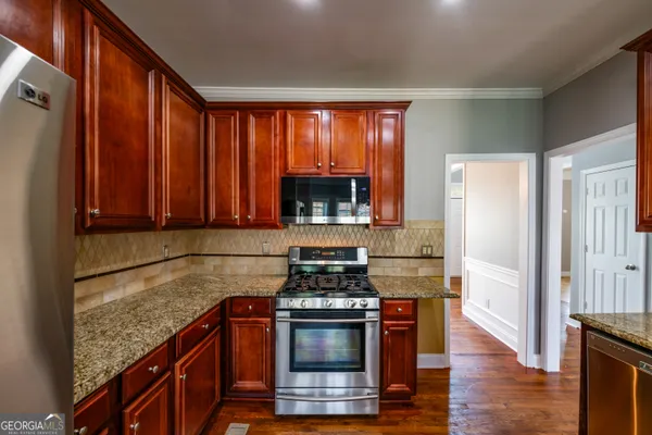 a kitchen with granite countertop a stove and a wooden floors